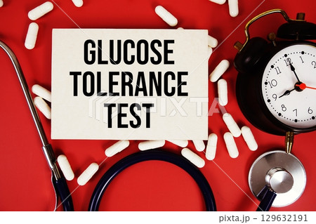 Glucose Tolerance Test text written on paper card with stethoscope and alarm clock on red background 129632191