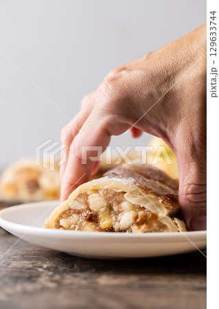 Hand taking two piece of apple strudel 129633744