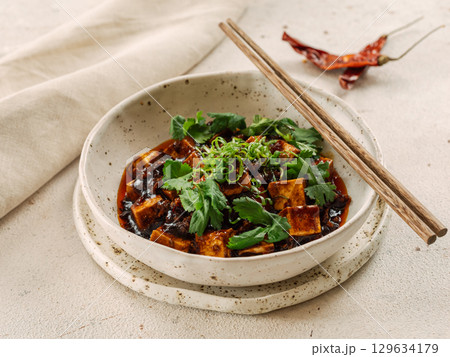 Spicy asian tofu salad or appetizer. Fried tofu decorated green onion - chinese dish with sauce. Serving Asian dish in restaurant in plate. Copy space 129634179