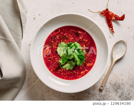 Traditional red soup borscht made with beetroot. National Russian and Ukrainian soup, kitchen, food. Tasty beetroot soup with greens in bowl on neutral pastel background. Top view, flat lay Traditional red soup borscht made with beetroot. National Russian and Ukrainian soup, kitchen, food. Tasty beetroot soup with greens in bowl on neutral pastel background. Top view, flat lay 129634190