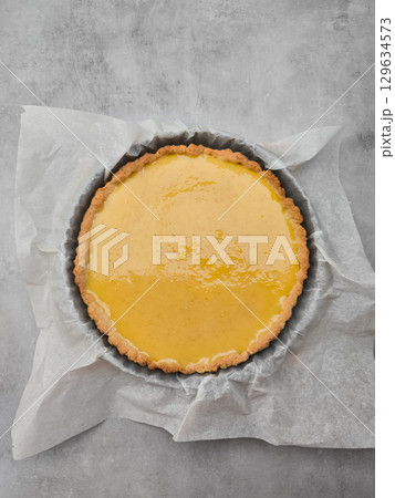 Delicious lemon tart resting on baking paper in a cake pan 129634573