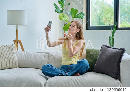 Smiling young teenage female taking selfie photo on smartphone Smiling young teenage female taking selfie photo on smartphone 129636012