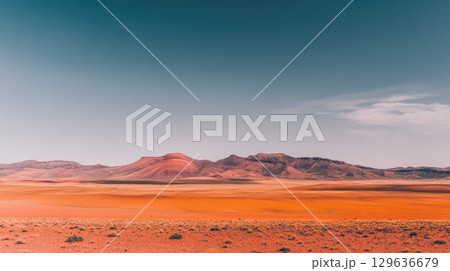 Vast desert landscape with vibrant colors under a clear sky at midday 129636679