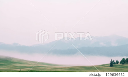 Misty morning landscape with rolling hills and distant mountains in serene nature 129636682