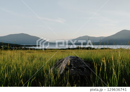 Scenic view of mountains and tranquil lake surrounded by green grass at sunset 129636741