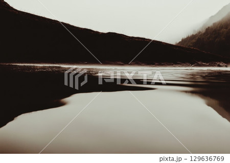 Serenity of a misty lake at twilight reflecting soft mountains in twilight calmness Serenity of a misty lake at twilight reflecting soft mountains in twilight calmness 129636769