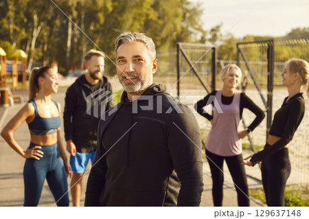 Portrait of smiling mature sporty man looking at camera after fit exercises in nature in the park. 129637148