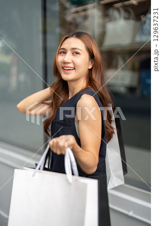 Black Friday shopping delight. Woman smiling with shopping bags in hand. Black Friday shopping delight. Woman smiling with shopping bags in hand. 129637231
