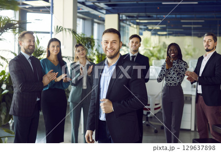 Smiling boss and business leader man with team of people applauding in background. 129637898