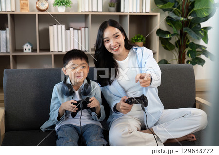 Gaming Together. Mother and son enjoying video games on the couch. Gaming Together. Mother and son enjoying video games on the couch. 129638772