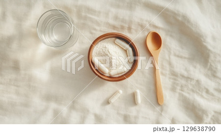 Flatlay of anti-aging supplements, collagen capsules and ceramic bowl with powder on linen fabric and minimal beige background with natural wellness styling 129638790