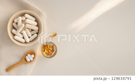 Flatlay of anti-aging supplements, collagen capsules and ceramic bowl with powder on linen fabric and minimal beige background with natural wellness styling 129638791