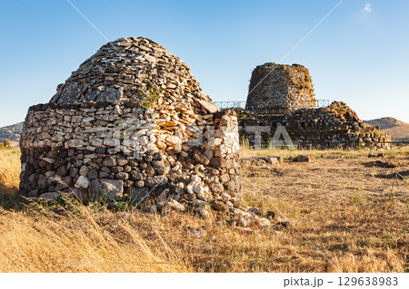 Nuraghe Santu Antine complex with ancient dome-shaped and tower structures in Sardinian countryside at sunset 129638983