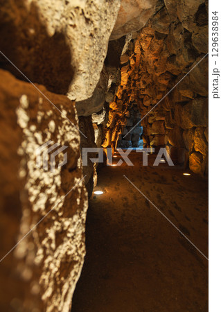 Interior stone corridor inside prehistoric Nuraghe in Sardinia illuminated by warm spotlights 129638984