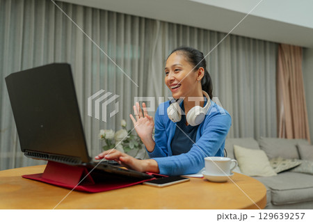 A Cheerful Woman Engaging Actively in an Online Meeting While at Home, Showing Comfort A Cheerful Woman Engaging Actively in an Online Meeting While at Home, Showing Comfort 129639257