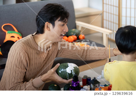 Creative Halloween Crafting with Child. Father and son painting pumpkins together. Creative Halloween Crafting with Child. Father and son painting pumpkins together. 129639616