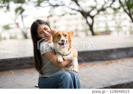 Happy moments. Woman cuddling her corgi dog on park steps. Happy moments. Woman cuddling her corgi dog on park steps. 129640025