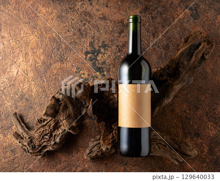 Bottle of red wine and old weathered snags on a brown vintage background. 129640033