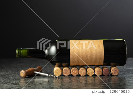 Corkscrew and bottle of wine on a black stone table. 129640036