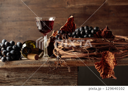 Red wine with grapes on an old wooden table. 129640102