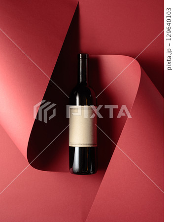 Bottle of red wine with old empty label on a red background. Bottle of red wine with old empty label on a red background. 129640103