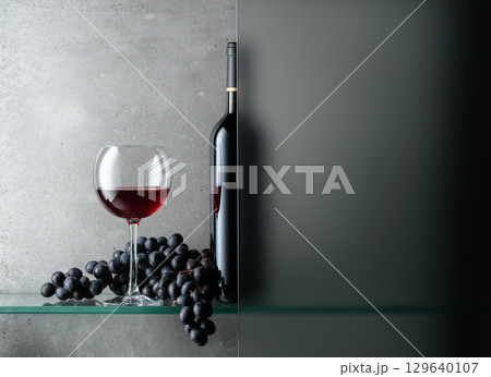 Bottle and a glass of red wine with a bunch of blue grapes. Bottle and a glass of red wine with a bunch of blue grapes. 129640107