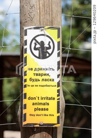 A Cautionary Sign Advising Visitors Not to Irritate Animals with Images and Text in English and Ukrainian to Encourage Respectful Behavior Toward Wildlife in Their Enclosure A Cautionary Sign Advising Visitors Not to Irritate Animals with Images and Text in English and Ukrainian to Encourage Respectful Behavior Toward Wildlife in Their Enclosure 129640209