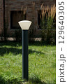 Modern Outdoor Lighting: A Contemporary Black and White Lamp Surrounded by Lush Green Grass in a Tranquil Garden Setting 129640305