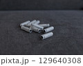 A Collection of Gray Plastic Tubes Spread on a Dark Surface, Ideal for Various Applications, Showcasing Their Unique Design and Textured Surface in a Clean, Minimalist Setting 129640308
