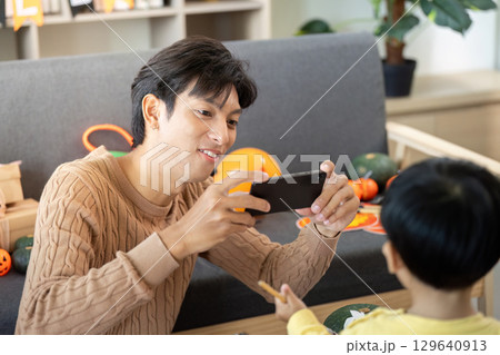 Capturing Memories. Father taking photos of son during Halloween crafting. Capturing Memories. Father taking photos of son during Halloween crafting. 129640913