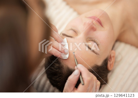 Professional cosmetology procedure for cleansing pores and skin from defects in a beauty salon. Close up shot of using facial metal device for the mechanical cleaning of skin Professional cosmetology procedure for cleansing pores and skin from defects in a beauty salon. Close up shot of using facial metal device for the mechanical cleaning of skin 129641123