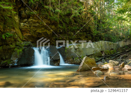 Small waterfall in Ukrainian Carpathian Mountains. Beautiful view of waterfall in mountains in sunny day 129641157