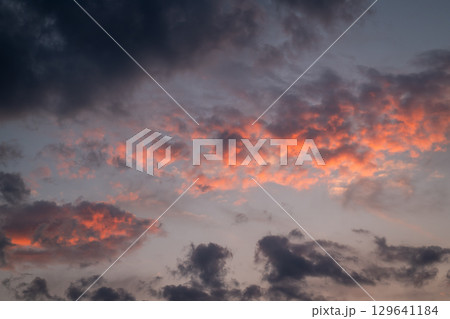 Vivid colors in burning sky after sunset, orange and dark blue clouds. Beautiful cloudscape of dramatic clouds 129641184