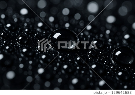 Detailed close-up of dark water droplets with high gloss effect on black background 129641688