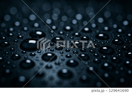 Macro shot of turquoise water droplets with even spacing on a smooth surface in soft lighting 129641690