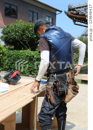 大工さんが腰袋から右手で道具を取り出している 129646417