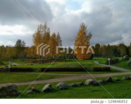 A scenic park landscape featuring lush, green grass and trees displaying autumn foliage with yellow and orange leaves A scenic park landscape featuring lush, green grass and trees displaying autumn foliage with yellow and orange leaves 129646852