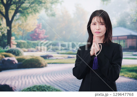 喪服を着て数珠を持って手を合わせる女性 喪服を着て数珠を持って手を合わせる女性 129647768
