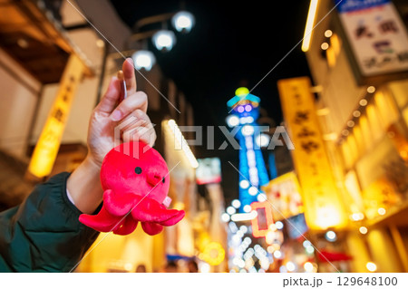 Pink octopus souvenir in hand at night in Shinsekai Osakas, Japan 129648100