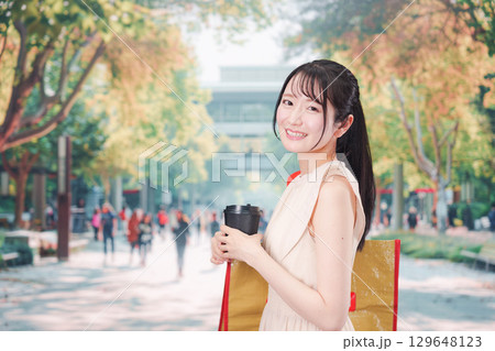 コーヒーを飲みながら外を歩く若い学生 コーヒーを飲みながら外を歩く若い学生 129648123
