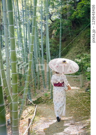 和傘を差し、着物姿で竹林の小径を散策する女性の後ろ姿 129648486