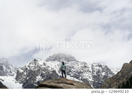 asian man standing on top of rock looking at peak of snow mountain 129649210