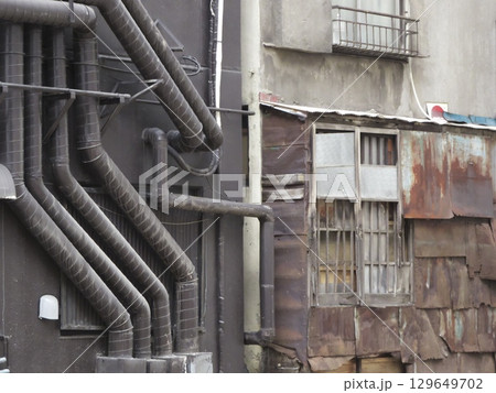 モダンな配管と錆びたトタン壁、新旧が入り混じる裏路地 129649702