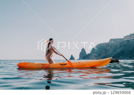 Kayaking Woman Ocean Santorini - A woman paddles a kayak in the ocean near Santorini, Greece. 129650008