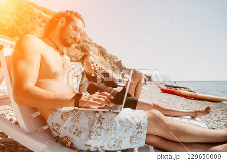 Man Beach Laptop - Man working on his laptop on the beach on a sunny day. 129650009