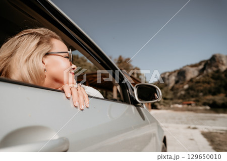 Woman Looking Out a Car Window on a Sunny Day 129650010
