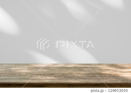 Empty wood table top on white wall texture with tree leaves shadow background 129653050