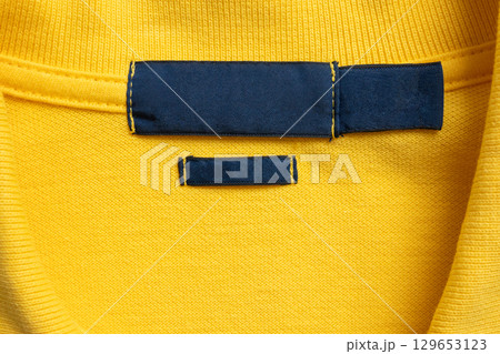 Blank blue laundry care clothes label on yellow shirt fabric texture background 129653123