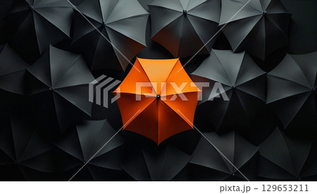 Orange umbrella standing out from crowd of black umbrellas 129653211