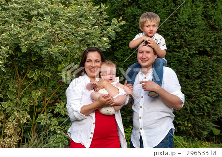 Smiling parents pose with baby and toddler on shoulders 129653318